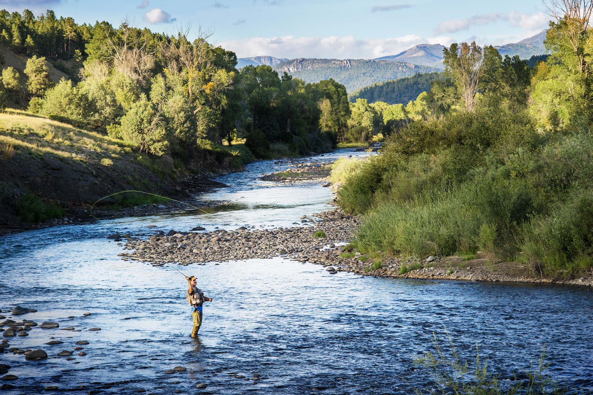 Man fly-fishing in the river near the 55+ community he found in a home search with the best real estate agent. 