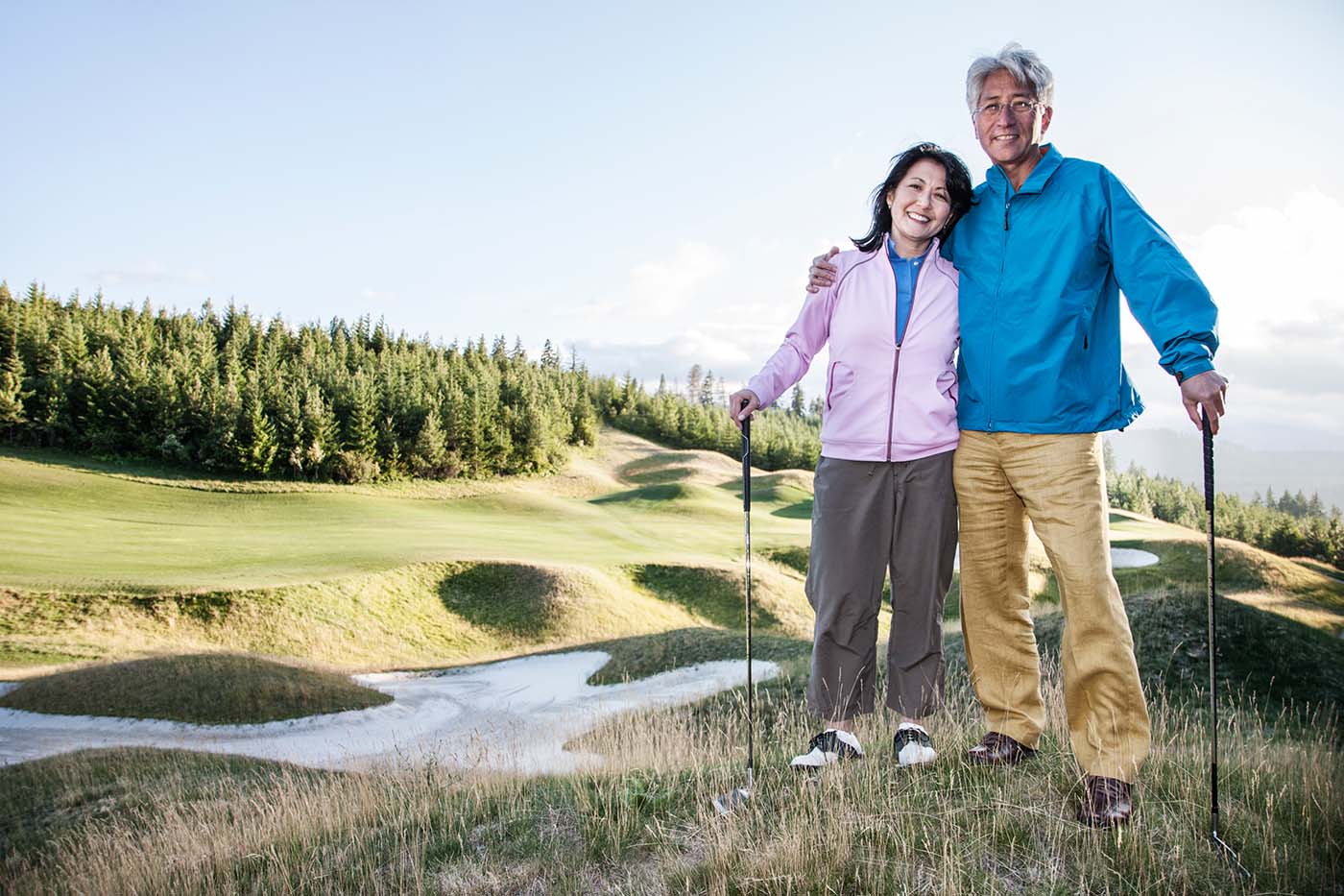 55+ couple enjoy the great outdoors by playing golf on a lakeview golf course for their daily activities