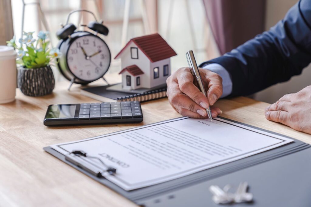 Signing real estate contract in front of a blurred clock, symbolizing the urgency of Idaho real estate deadlines.