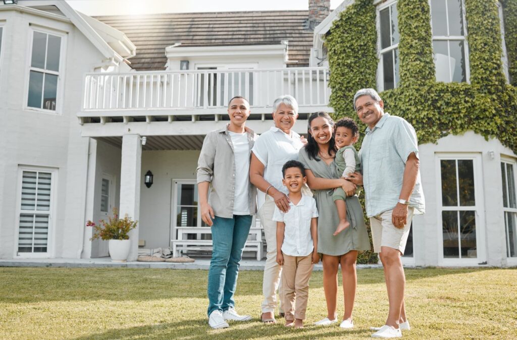 Happy diverse family standing in front of modern house backyard